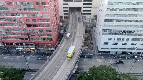 traffic passing through a car park building in downtown hong kong, with city mega buildings, aerial view