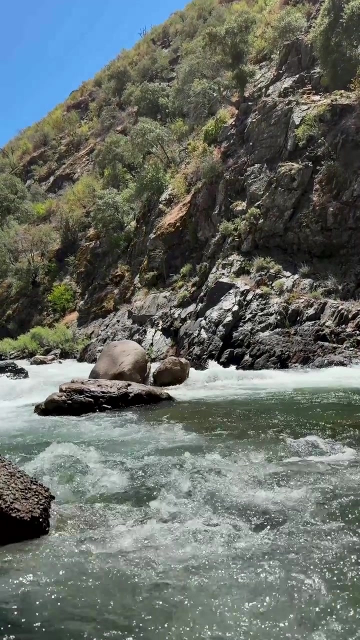Un'inquadratura verticale ampia di un fiume che scorre attraverso un paesaggio roccioso