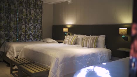 comfortable hotel room featuring double and single double beds, elegant bedside lighting, and stylish floral curtains, creating a warm and inviting atmosphere for guests