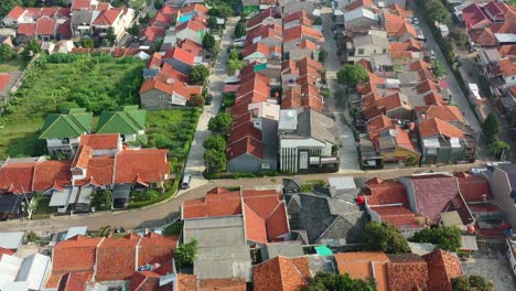 Motorbike-driving-through-local-Indonesian-neighborhood-in-Bandung-at-sunrise,-aerial