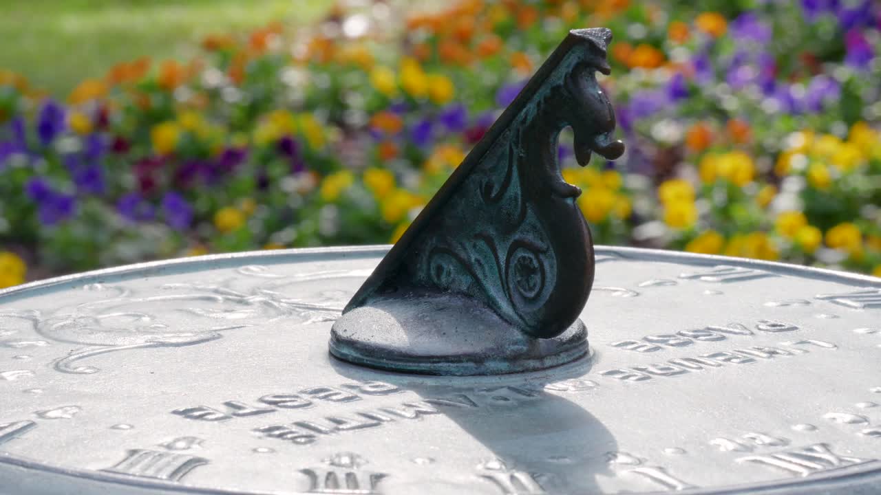 афины, штат га - 9 октября, 2018: медленная панорама узкого кадра на солнечных часах в расслабляющем саду с цветущими цветами прекрасным и солнечным весенним утром