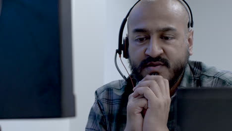 Bald-Bearded-UK-Asian-Male-Wearing-Headset-In-Conversation-With-Customer