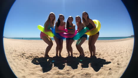 group of young women on a beach with inflatable rings