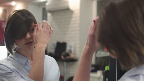 Mujer-Adulta-Con-Camisa-Mirándose-En-El-Espejo-Después-De-Cortarse-El-Pelo-Y-Tocarse-El-Pelo.-Filmado-En-Cámara-Lenta