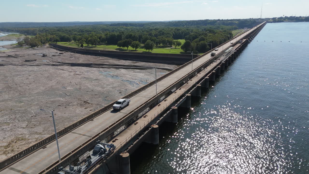 Pensacola Dam spillway and reservoir water flowing through northeastern Oklahoma, aerial pullback as cars cross on road