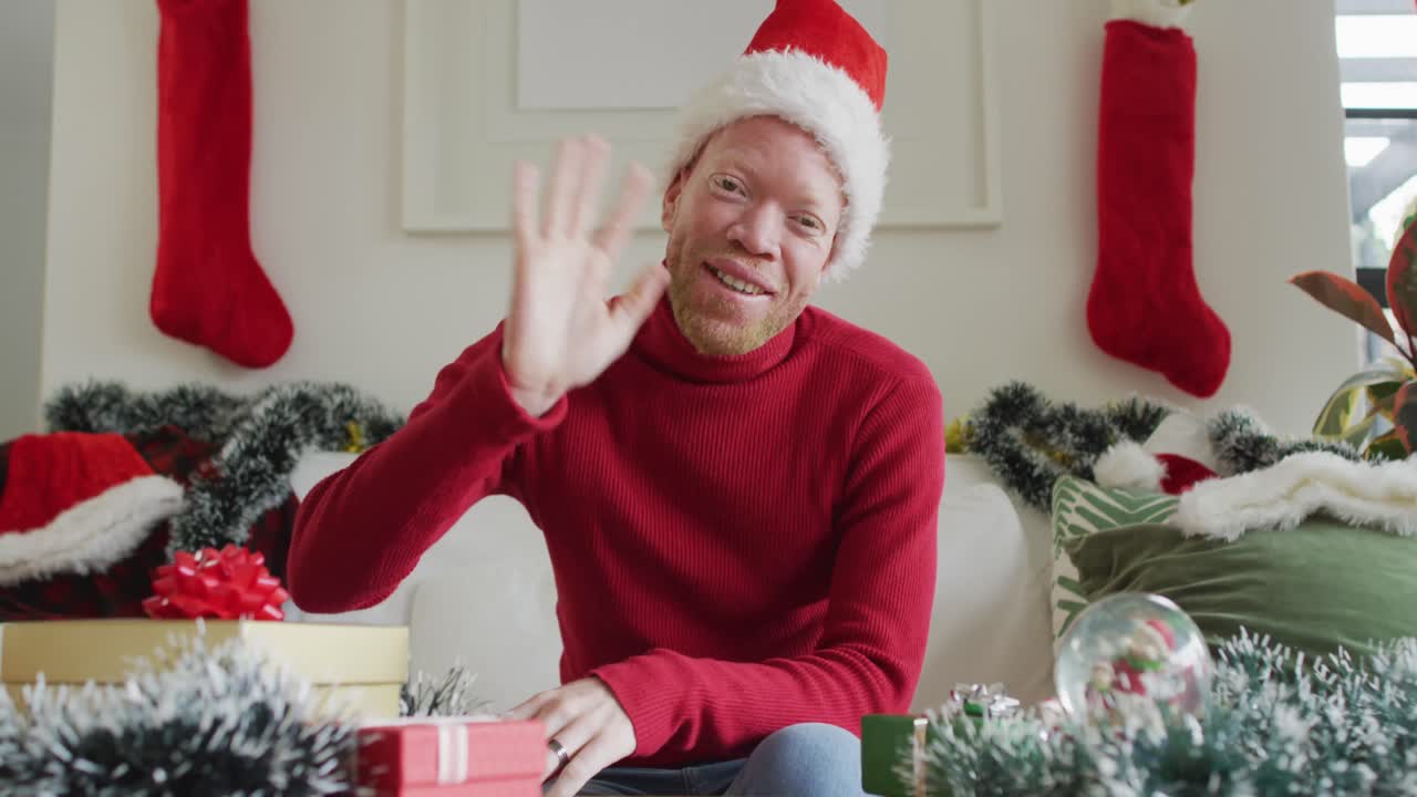 hombre afroamericano albino feliz con sombrero de papá noel haciendo una videollamada en navidad