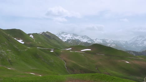 Aerial:-beautiful-Alps-valley,-remote-landscape-with-snowy-mountain-backdrop