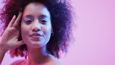mujer biracial con cabello oscuro en luz azul y rosa con espacio de copia, cámara lenta