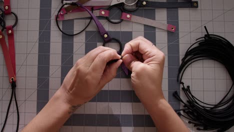 from a bird's-eye view, observe a skilled hispanic artisan meticulously crafting leather collars by hand in her workshop, showcasing her expertise and dedication to her craft