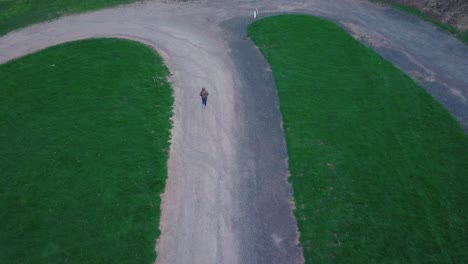 vista aérea de una excursionista caminando por el sendero con exuberantes campos