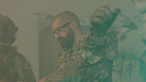 homens concentrados vestindo uniforme de camuflagem e coletes à prova de balas verificando armas e rifles