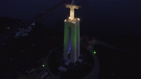 Cristo-Rei-statue-in-front-of-Ponte-25-de-Abril-during-blue-hour,-aerial