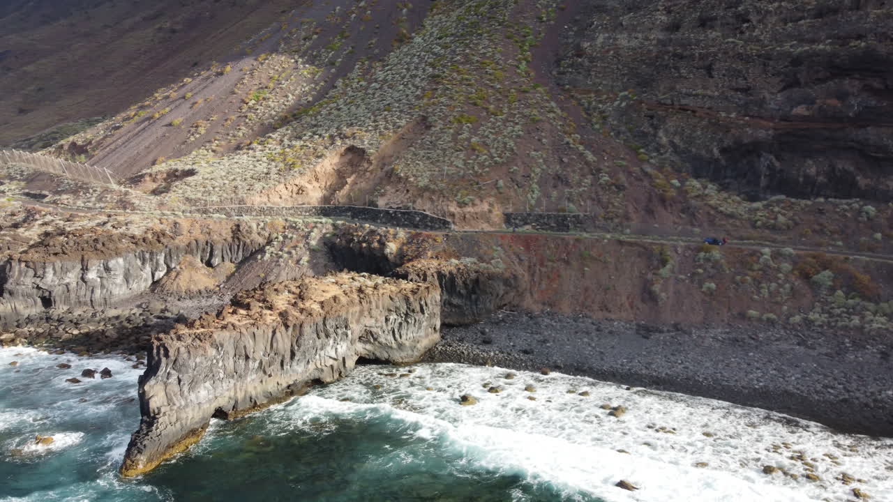 해안의 바위 절벽은 맑은 날에 차가 도로를 따라 지나가는 청록색 물로 바다의 파도에 의해 씻겨지고, 이에로 섬 - 공중 촬영
