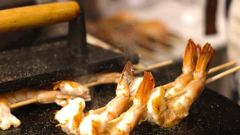 close-up of shrimp skewers sizzling on a griddle, showcasing their golden-brown texture.