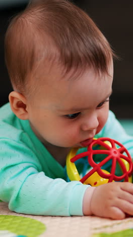 healthy active little toddler looking attentively on his toys. cheerful baby claps his hand over the floor. blurred backdrop. vertical video