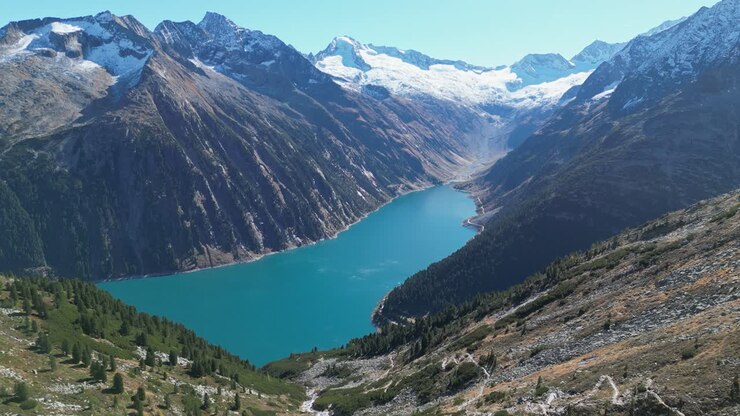 Lago di montagna Schlegeis presso il sentiero escursionistico Olpererhütte nelle Alpi della Zillertal, Austria - Aerea 4k