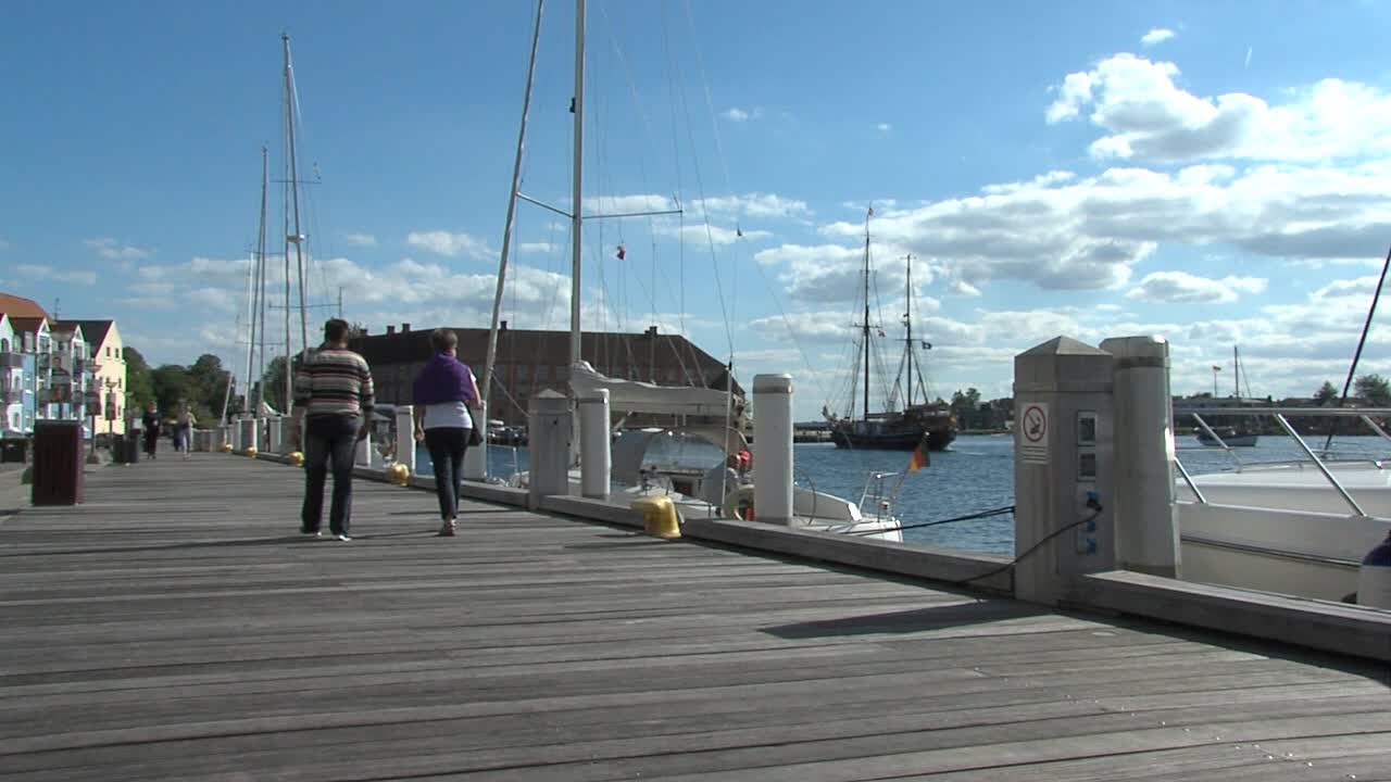A scenic view of a pier with boats and people