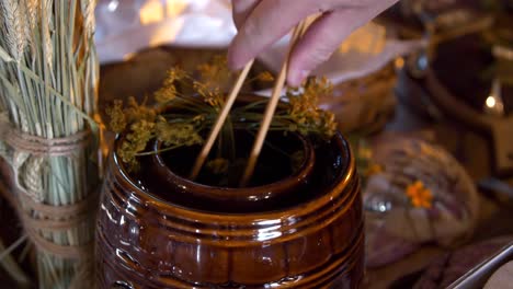 pickled cucumbers being taken out of a clay container using wooden tongs