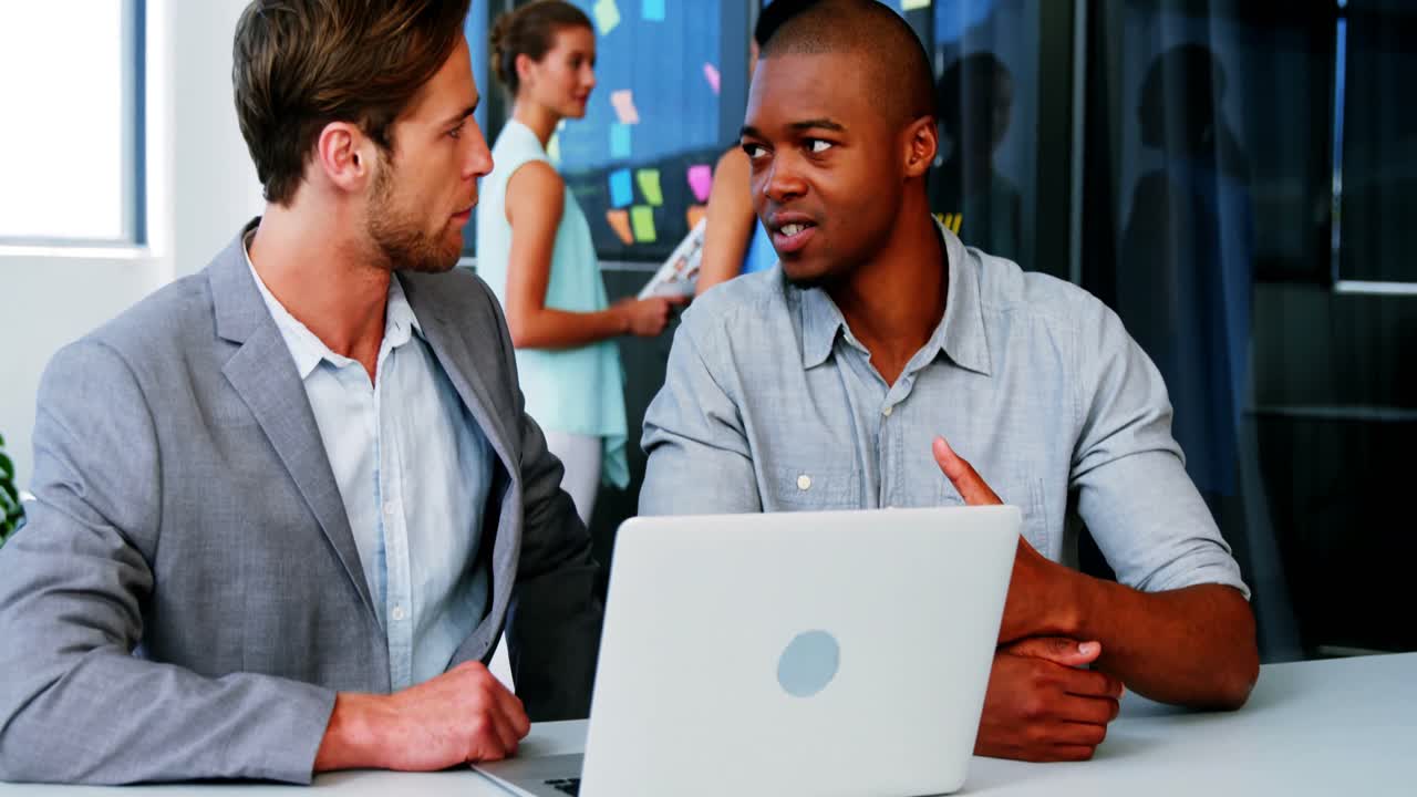 Business executives discussing over laptop