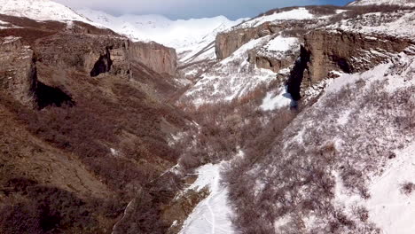 Erhebt-Sich-über-Eine-Schroffe-Schlucht-Mit-Klippen-Und-Schneebedeckten-Bergen-Vor-Sich