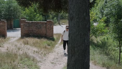 young man walking with guitar on street near forest