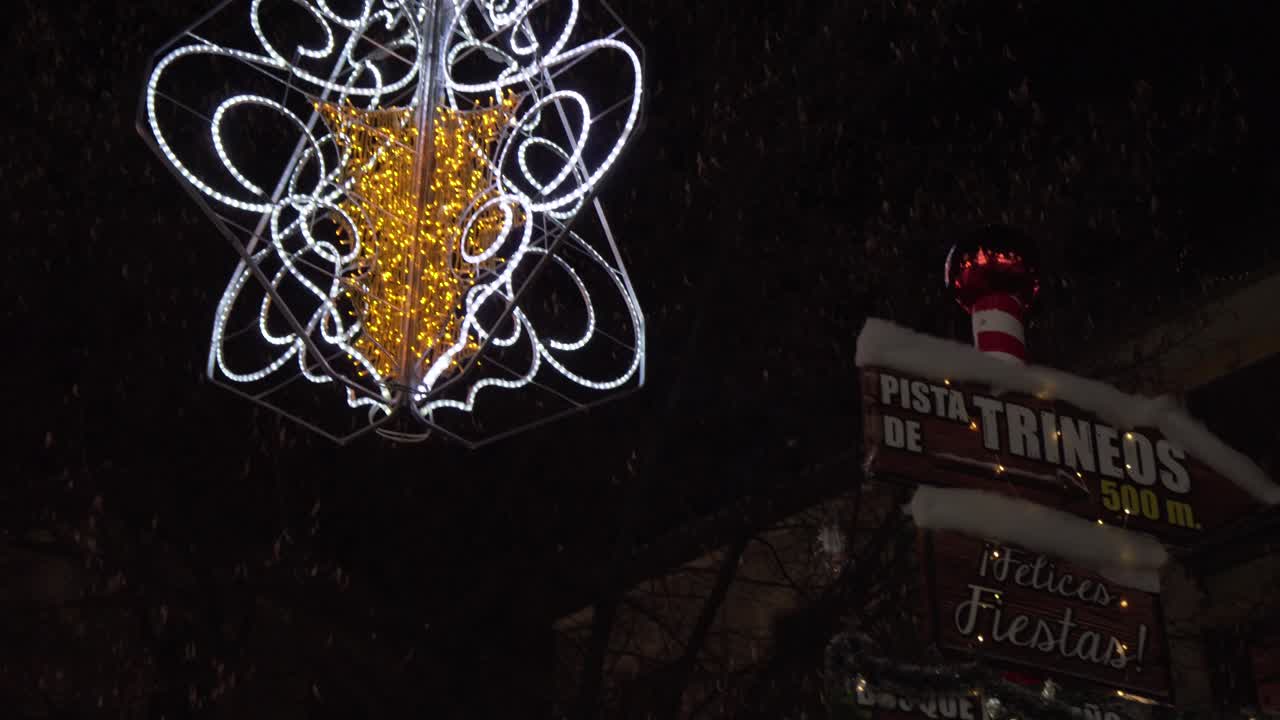 A beautiful yellow and gold Christmas decoration hanging by a signage in Granada, Spain - tilt down