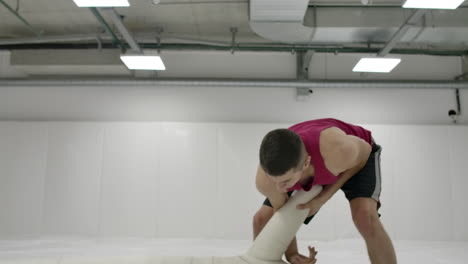 Two-Male-wrestlers-perform-a-dummy-throw-on-mats-in-slow-motion.-Professional-grappling-fighters