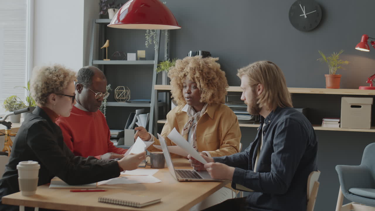 Diverse Colleagues Speaking and Working with Papers on Meeting