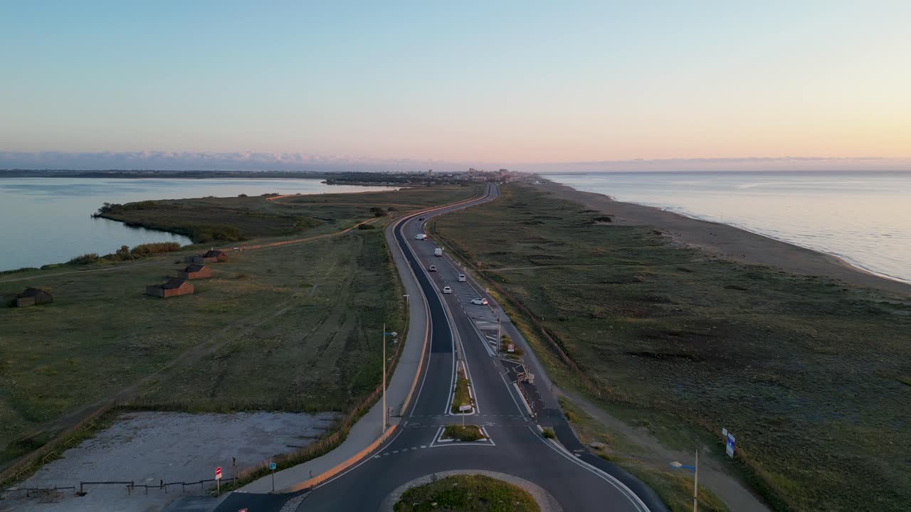 Aerial: Flying forward a lonely road during sunset, next to the coastline in France