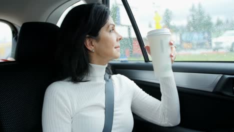 Mujer-Sentada-En-El-Coche-Sosteniendo-Un-Vaso-Desechable