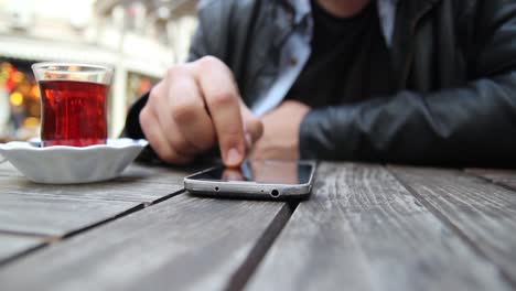 young man using his smartphone in a cafe close up hands 1