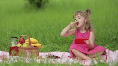 weekend at picnic. girl on grass meadow play online games on mobile phone. social network, chatting