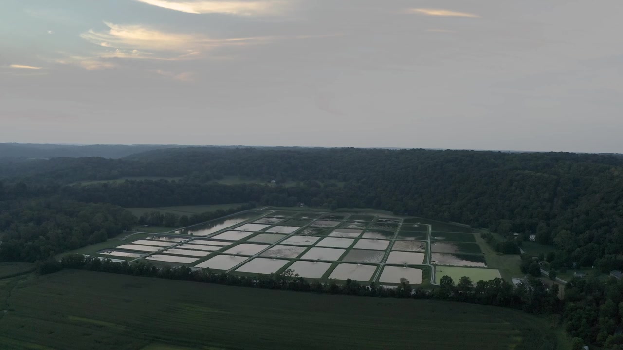 Una vista panoramica di una piscicoltura a griglia al tramonto nella campagna.
