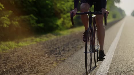 Vista-Frontal-Recortada-De-Un-Ciclista-Masculino-Monta-En-Bicicleta-Por-Una-Pista-Vacía-Por-La-Mañana
