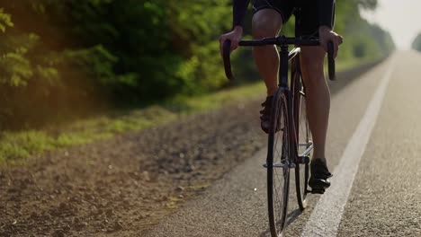 cropped front view of a male cyclist rides bicycle along an empty track in the morning