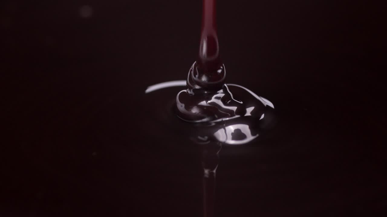 Chocolate pouring in a smooth, rich flow, detailed spiral dispersing into darkness, slow motion macro