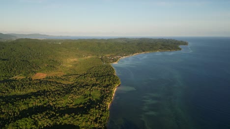 panoramic aerial drone shot of lush tropical provincial island facing idyllic turquoise cove at san andres, catanduanes, philippines during daytime.