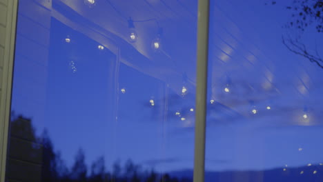 warm lights reflecting in a window at dusk with a calm, serene outdoor background