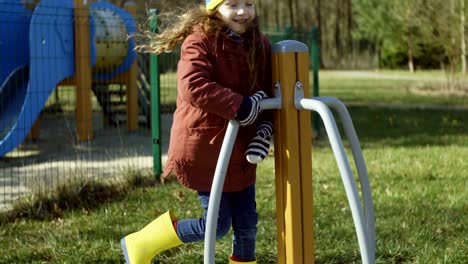 niña feliz de buen humor jugando en el patio de recreo. hembra encendiendo el carrusel y sonriendo. infancia despreocupada