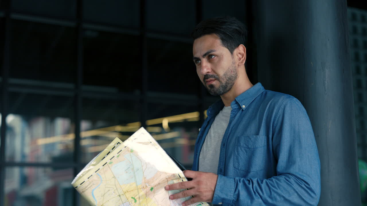 Man Looking at Map and Using Walkie-Talkie Indoors