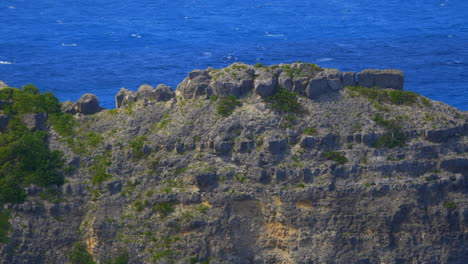 siguiendo la cresta de un acantilado rocoso desde la línea de flotación erosionada hasta la parte superior cubierta de hierba verde