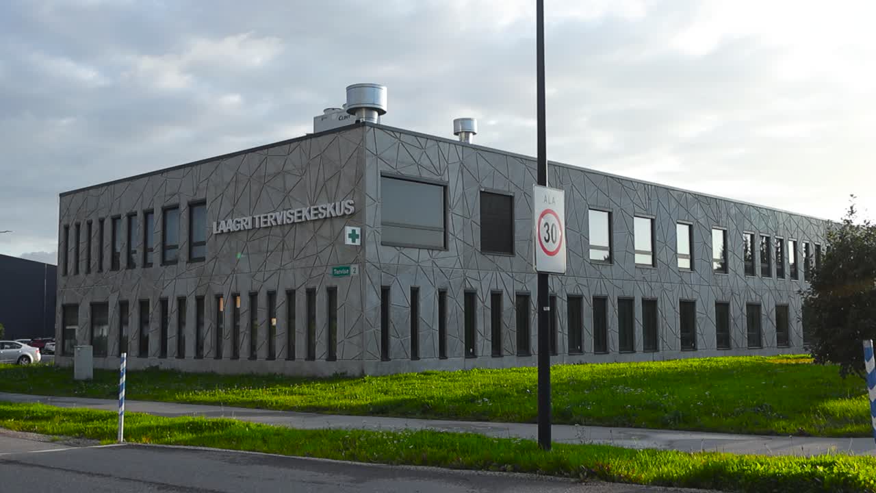 Beautiful footage of Laagri Health care center in Tallinn, Estonia, Europe during summer time with green grass and poppy stone roads surrounding it. Sky is cloudy and sun is shining during daytime.