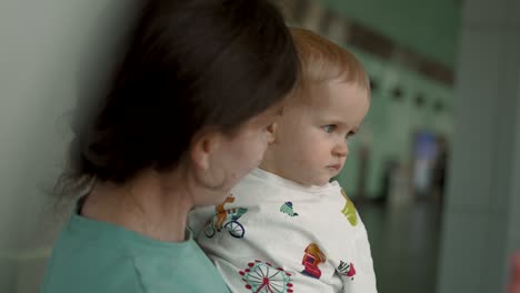 close-up of mother showing her son window view indoor of airport terminal.