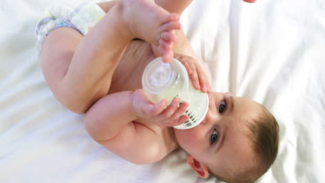 cute baby lying and drinking his baby''s bottle