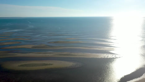 cape cod bay aerial drone footage of bay side beach at low tide with sand dunes and sun panning shot