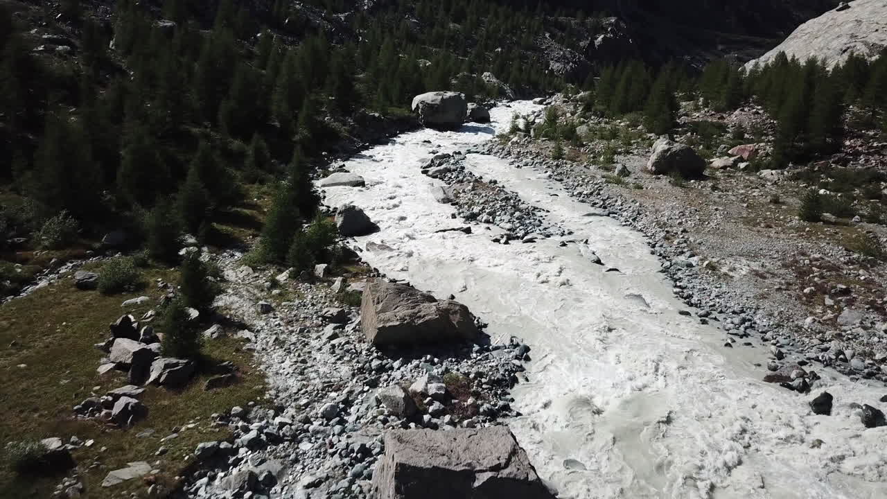 valle rocoso en los alpes suizos con un río fangoso en el centro, vista aérea de drones