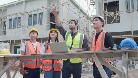 diverse team of civil engineers manager, architects and foreman, worker. while use laptop inspect discuss meeting building project and pointing on construction site.