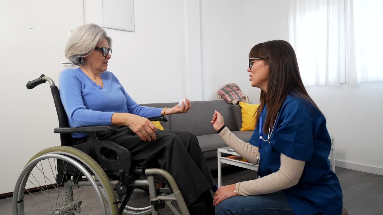 Badante aiuta un'anziana in sedia a rotelle con esercizi per le mani