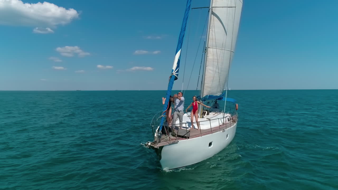 Young group of people have a rest on a yacht. Big yacht riding on the sea.