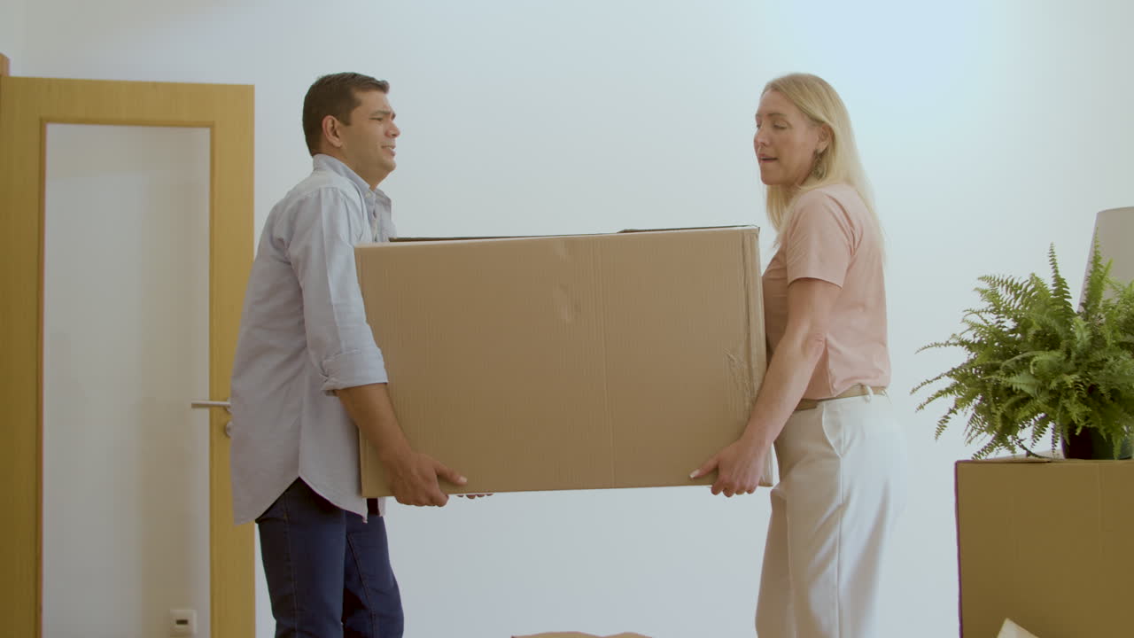 esposa y marido llevando una caja grande a una casa nueva juntos
